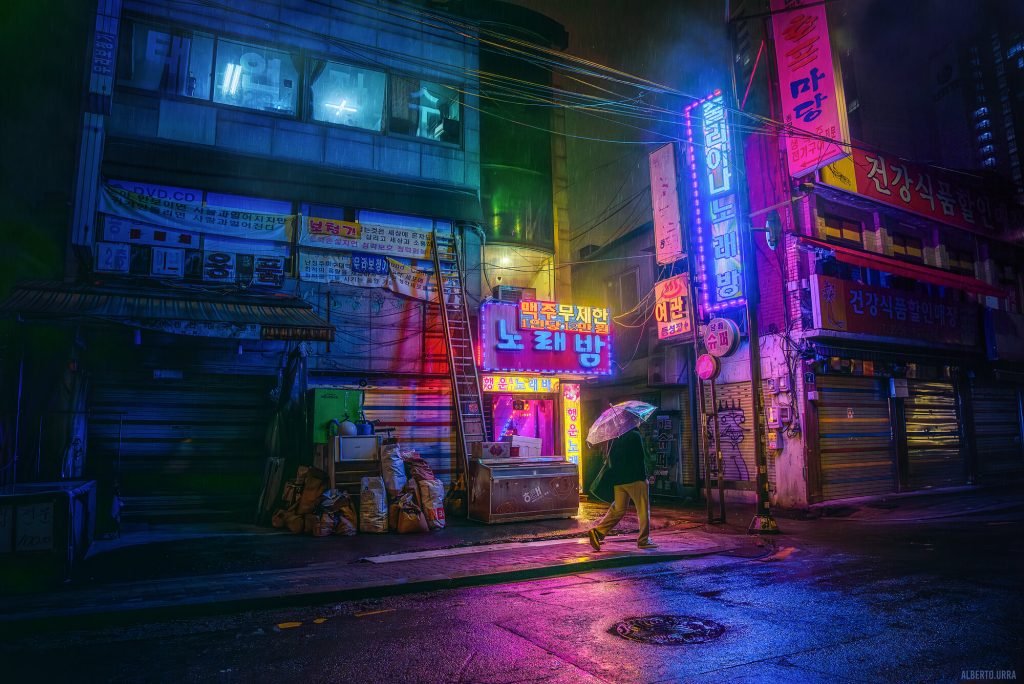 Fotografía Cyberpunk de una calle muy colorida, lloviendo, con una persona andando con paraguas