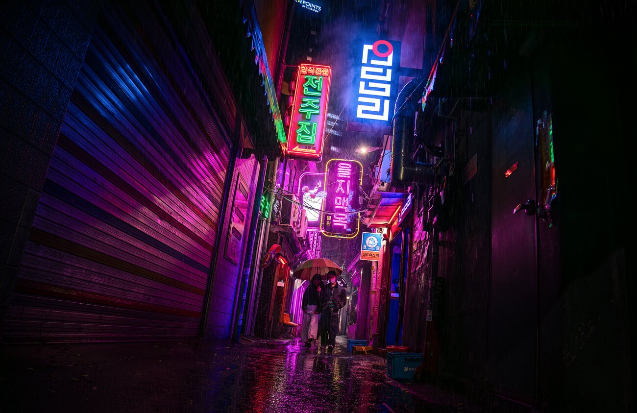 Callejón Cyberpunk en Seul, lloviendo con dos personas pasando con un paraguas